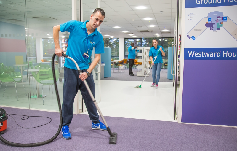 Commercial cleaners vacuuming and mopping inside office building