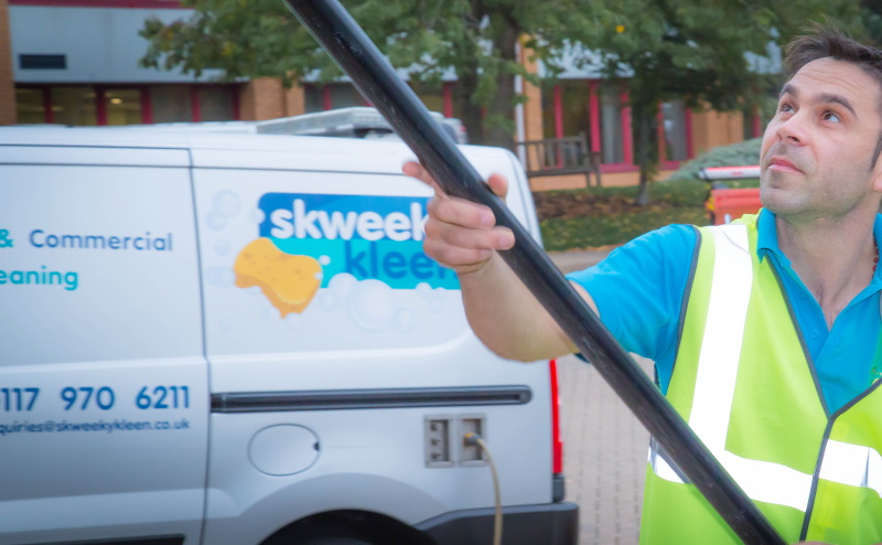 Commercial window cleaner working beside Skweeky Kleen van
