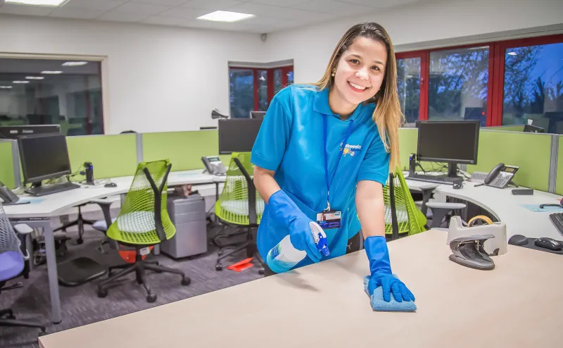 Professional office cleaner wiping desk in modern workplace