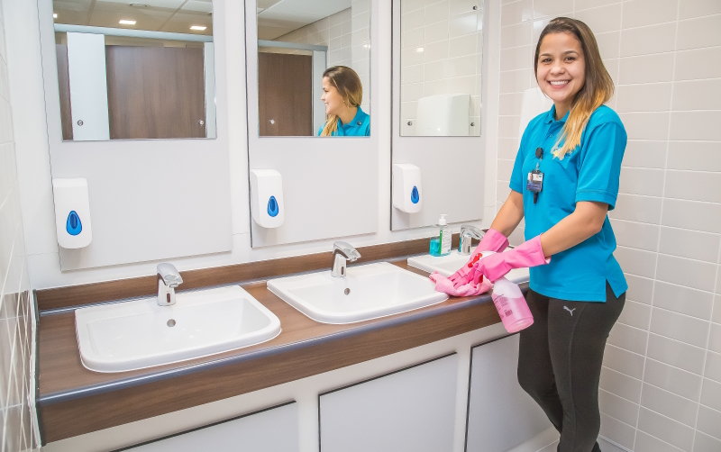 Commercial cleaner sanitising washroom sinks